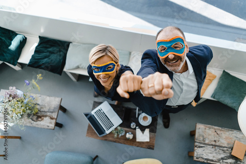 Businessman and woman wearing super hero masks, raising fists photo