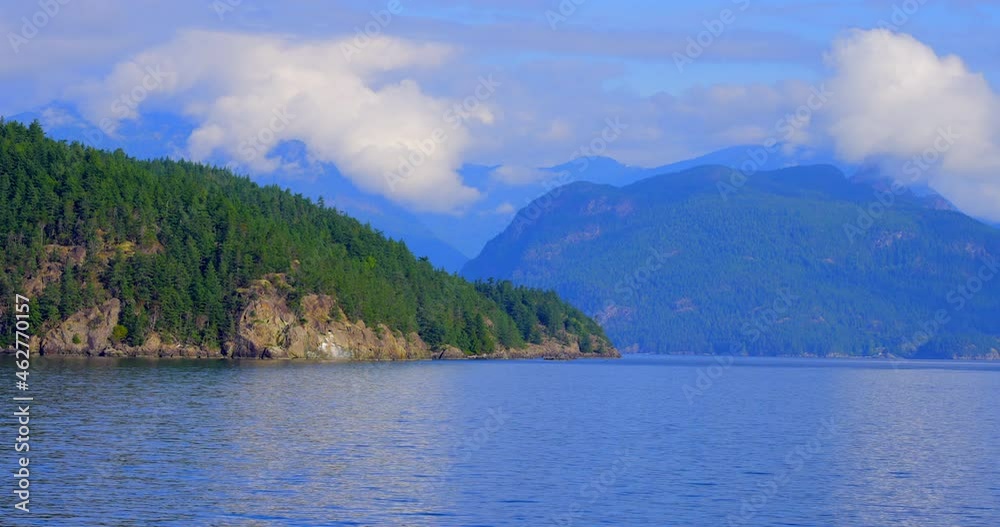 Establishing shot of ocean beach with rocks, pebbles and wood logs in slow motion at summer day in Vancouver, Canada, North America. Day time on September 2021. Still camera. ProRes 422 HQ. Establishing shot of ocean beach with rocks, pebbles and wood logs in slow motion at summer day in Vancouver, Canada, North America. Day time on September 2021. Still camera. ProRes 422 HQ.