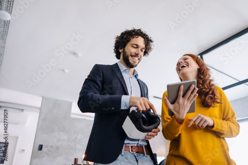 Happy businessman and businesswoman with VR glasses and tablet in office