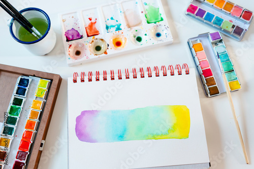 Abstract of rainbow water color painting with equipment on table photo