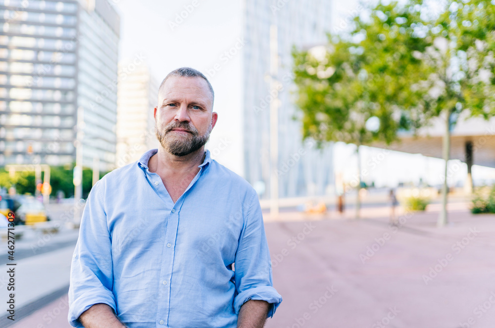Mature male entrepreneur standing on footpath in city Mature male entrepreneur standing on footpath in city