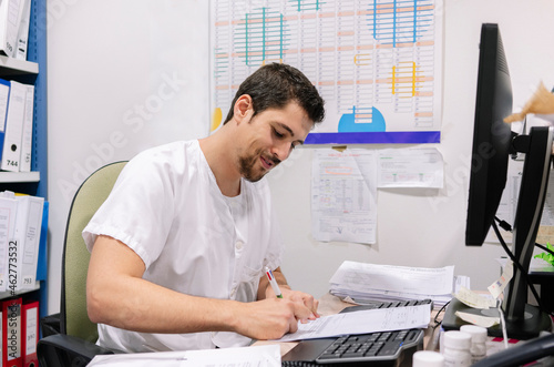 Wallpaper Mural Male doctor writing on document at desk in pharmacy Torontodigital.ca