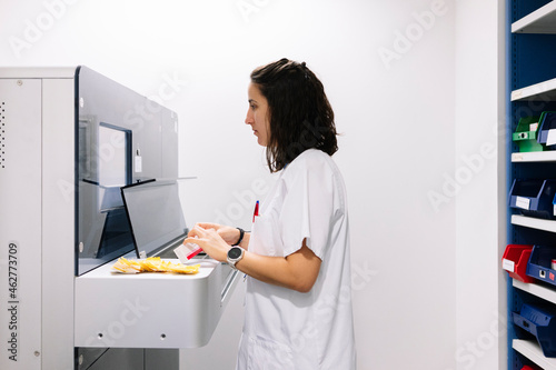 Female doctor using medication organizing machinery in pharmacy at hospital photo