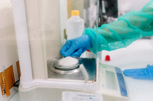 Hands of female scientist measuring powder medicine on scale in laboratory photo