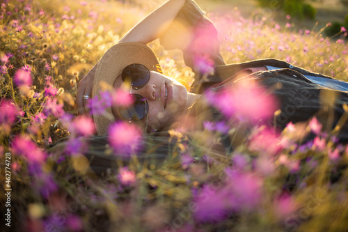 Young woman with sunhat lying on meadow at sunset photo