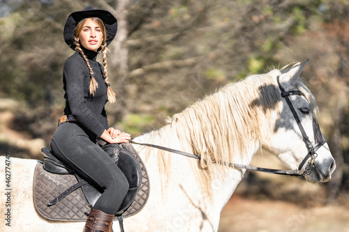 Portrait of woman horseback riding in paddock photo