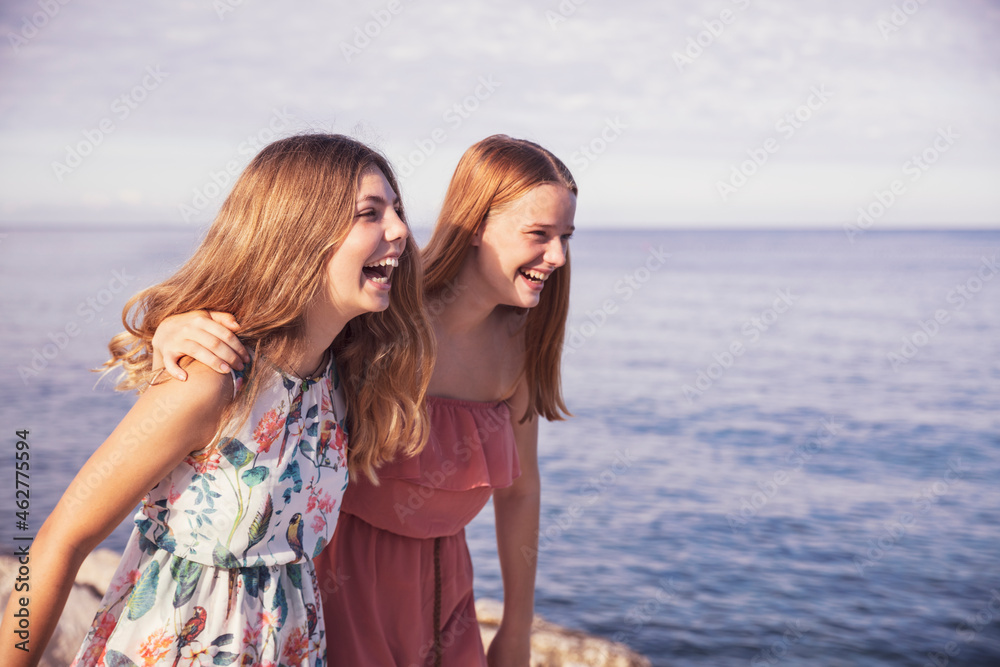 Friends laughing while standing on sidewalk during sunny day Friends laughing while standing on sidewalk during sunny day