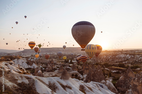 Hot air balloons flying over rocky landscape against clear sky in Goreme during sunset, Cappadocia, Turkey photo
