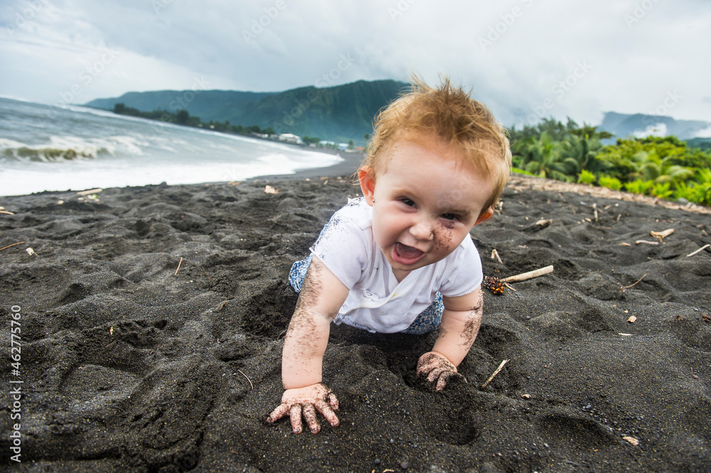 French Polynesia, Taharuu Beach, baby girl playing in black sand French Polynesia, Taharuu Beach, baby girl playing in black sand