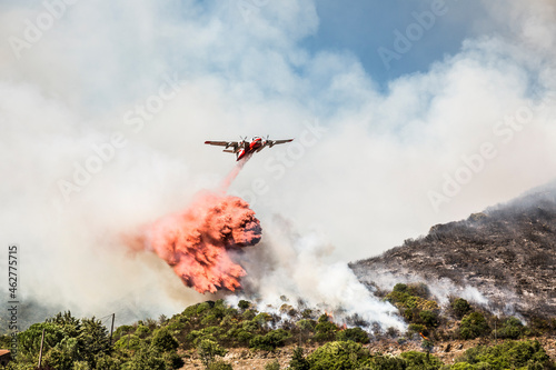 Aerial fire fighting aircraft dropping load of flame retardant on wildfire, Corsica, France photo