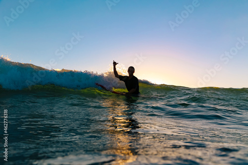 Surfer making surfer sign sitting on surfboard, Bali, Indonesia photo