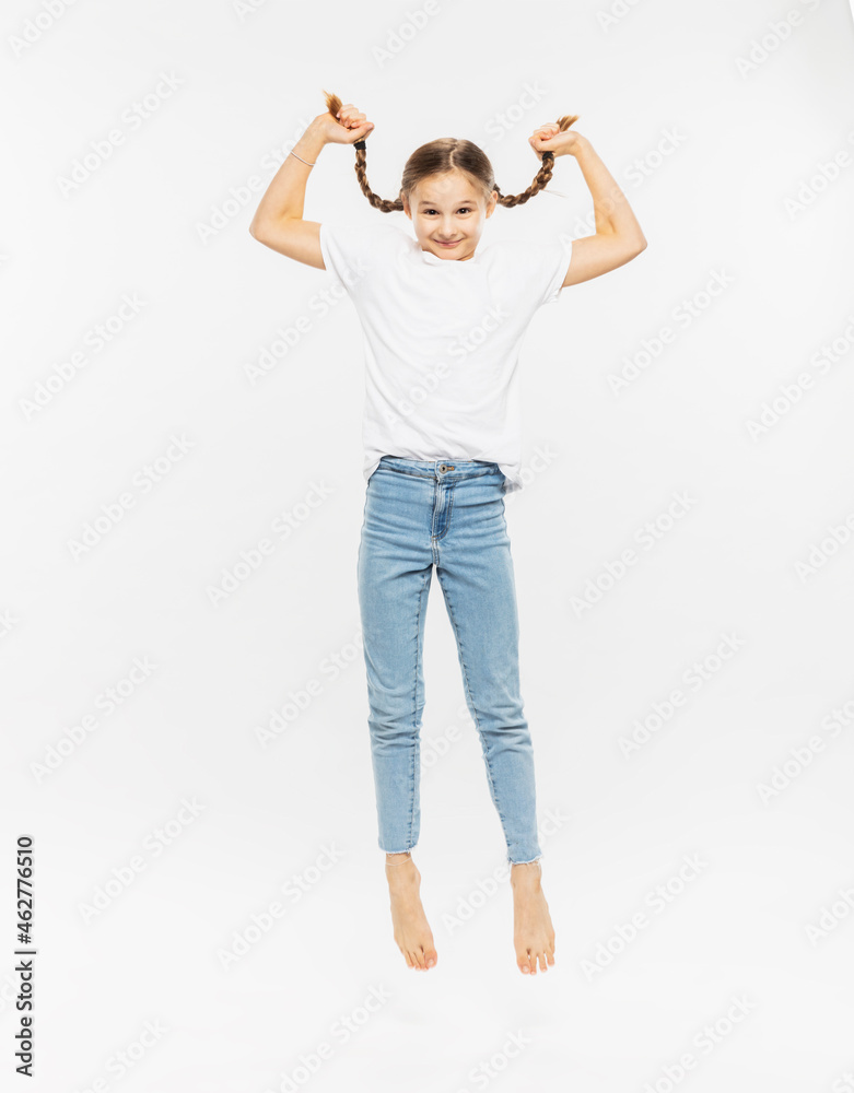 Girl holding her pigtail while jumping against white background Girl holding her pigtail while jumping against white background