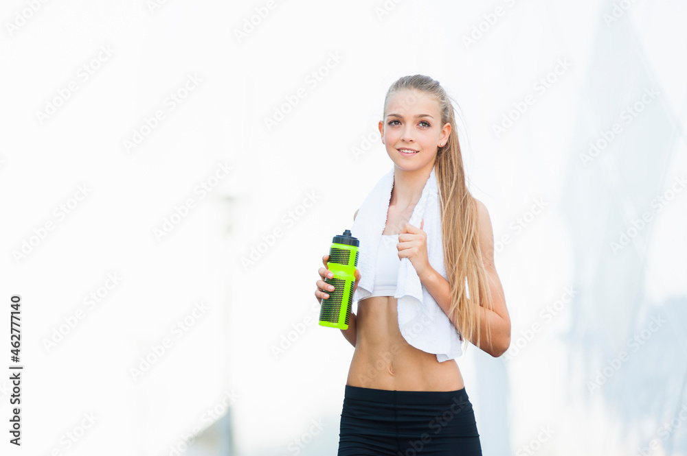 Female jogger with bottle and towel during break Female jogger with bottle and towel during break