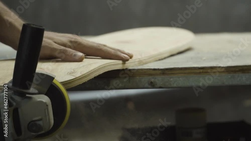 Craftsman shaping a brand new skateboard deck, using a sander photo