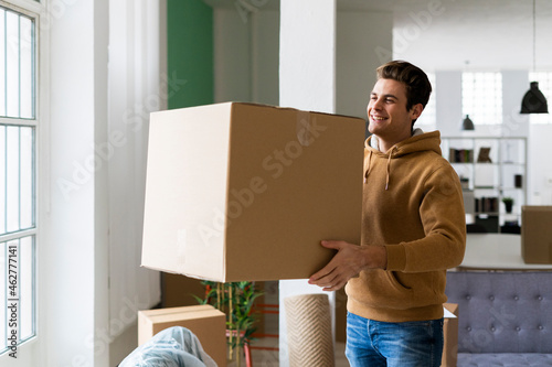 Happy young man carrying box in new loft apartment photo