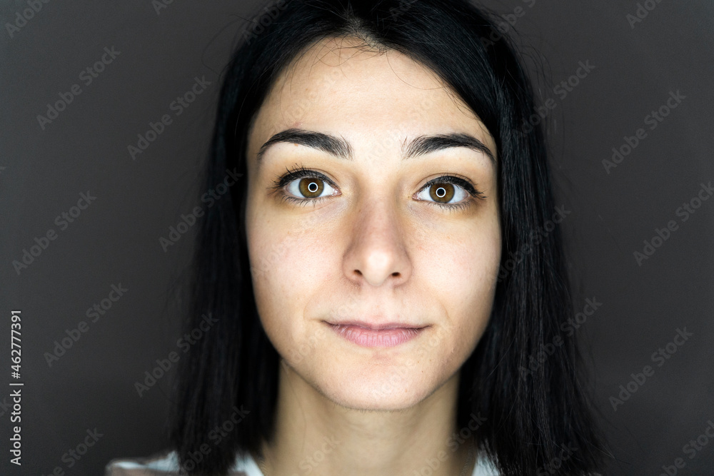 Beautiful young woman with blank expression against gray background Beautiful young woman with blank expression against gray background