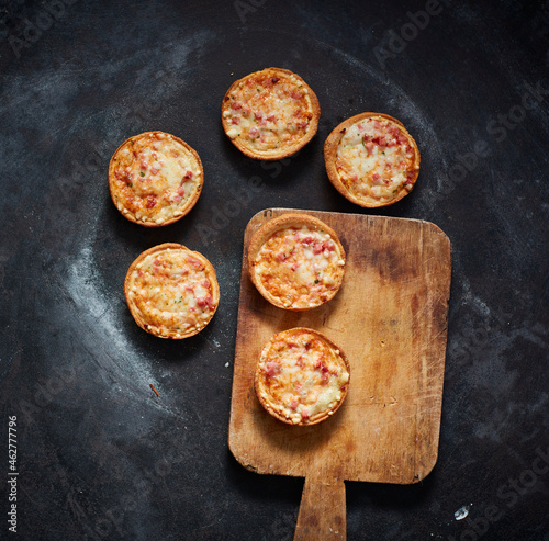 Spatula and mini pizzas with cheese, tomatoes and ham
