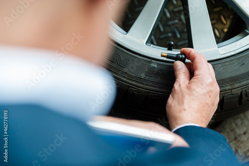 Senior businessman holding air valve by tire at store photo
