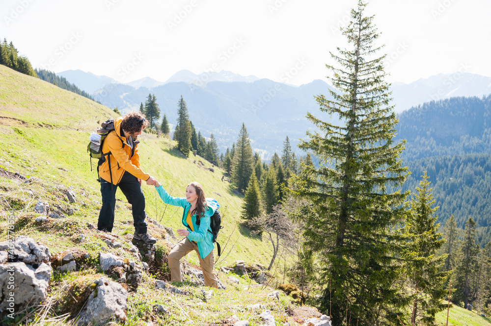 Man helphing his woman climbing rock, Wallberg, Bavaria, Germany Man helphing his woman climbing rock, Wallberg, Bavaria, Germany