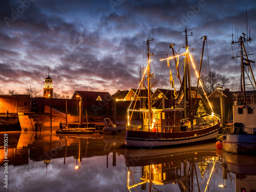 Germany, Lower Saxony, Landkreis Leer, Friesland, Ditzum, Ship illuminated for Christmas at dusk