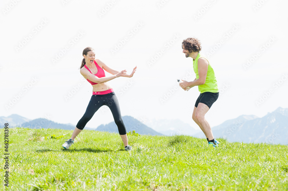 Jogger squirting water to woman, Wallberg, Bavaria, Germany Jogger squirting water to woman, Wallberg, Bavaria, Germany