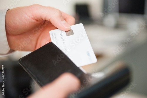 Hands of man holding wallet and blank white credit card