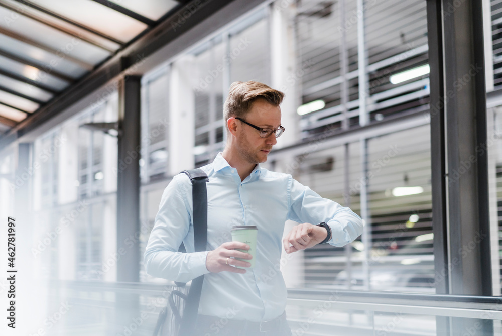 Businessman with coffee checking the time in city Businessman with coffee checking the time in city