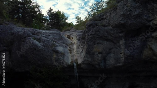 Rising Aerial of Small Waterfall Gently Streaming from Valley River photo