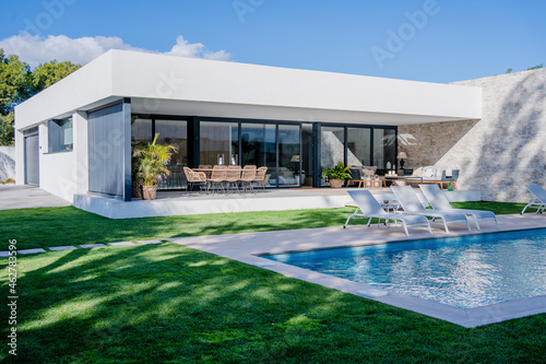 Empty lounge chairs at poolside against modern house photo