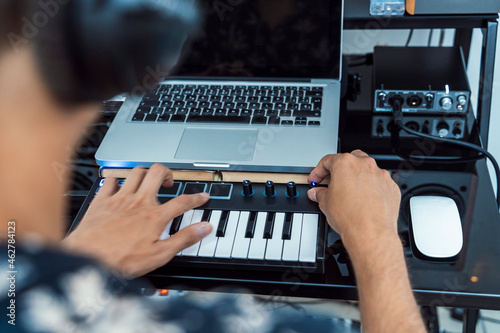 Man adjusting knob on midi keyboard over table