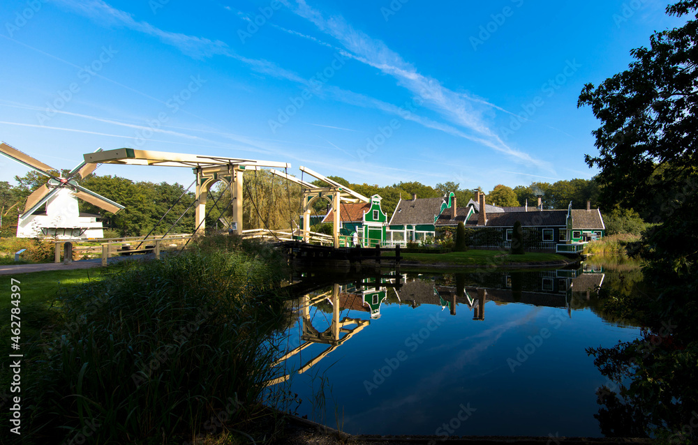 Historic dutch village with little green gable houses, windmill and drawbridge in front of a lake. Arnhem in the Netherlands. Tourism and vacations concept.