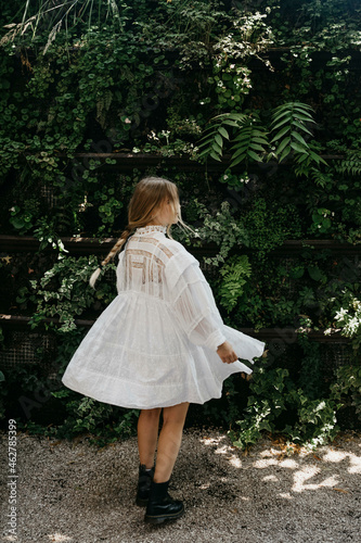 Blond young woman wearing white summerdress dancing outdoors photo