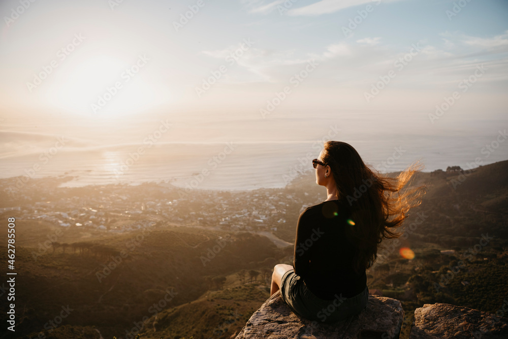 South Africa, Cape Town, Kloof Nek, woman sitting on rock at sunset