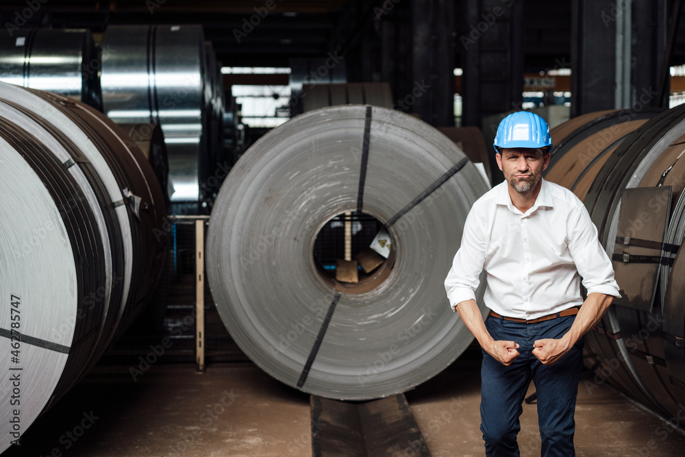 Businessman flexing muscles while standing in factory Businessman flexing muscles while standing in factory