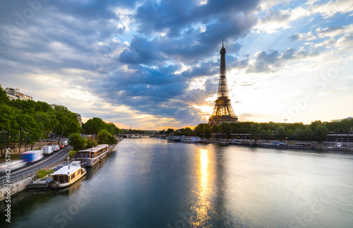 Eiffel Tower by Seine river against blue sky during sunrise, Paris, France