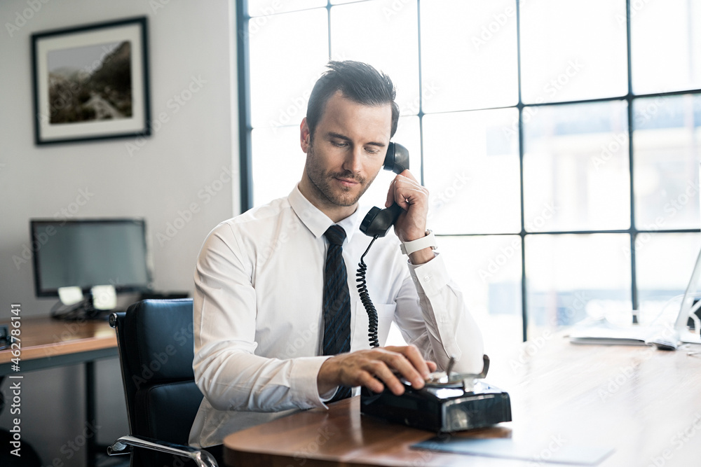 © steve brookland/Westend61 - Businessman in office using vintage retro telephone