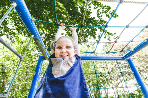 Smiling cute girl hanging from jungle gym at playground in park