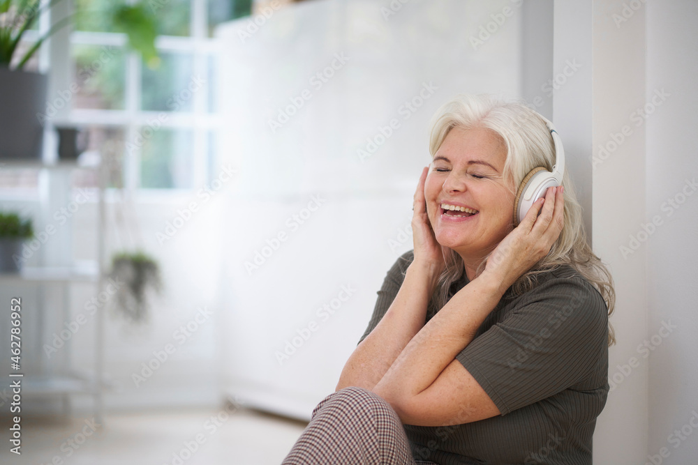 Happy senior woman enjoying music through headphones at apartment Happy senior woman enjoying music through headphones at apartment
