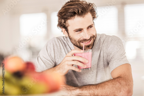 Young man smiling and drinking a fruit smoothie photo