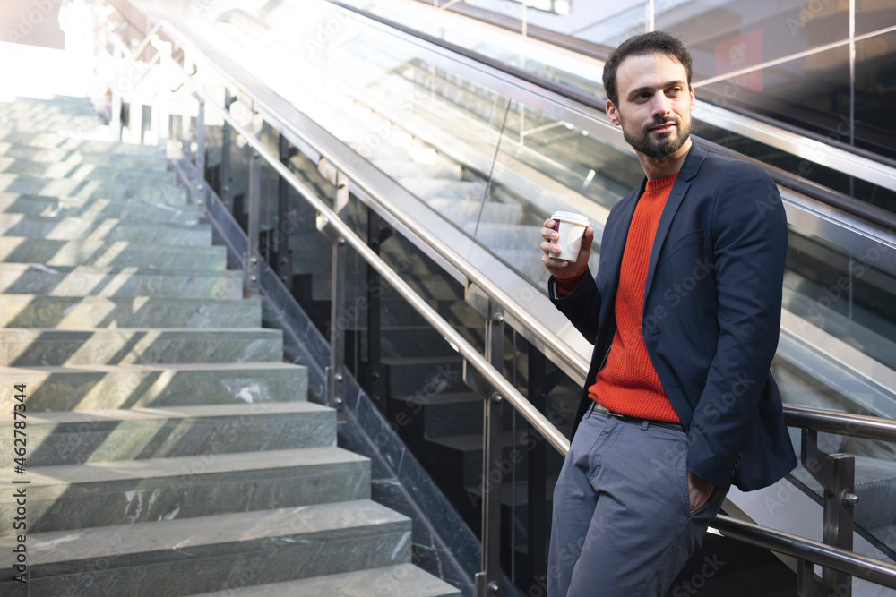 Confident entrepreneur drinking coffee while standing on staircase in city Confident entrepreneur drinking coffee while standing on staircase in city