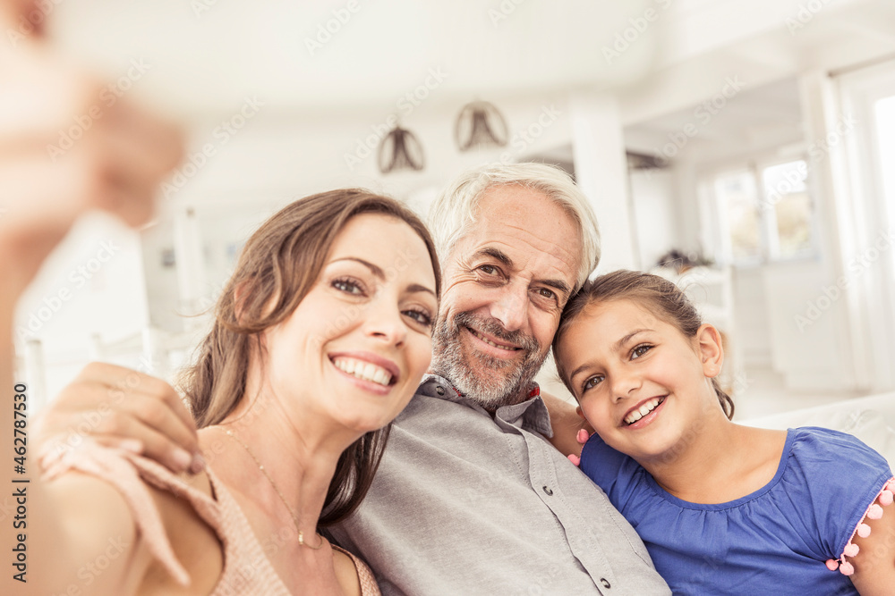 Happy family taking a selfie on couch in living room Happy family taking a selfie on couch in living room