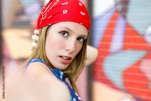 Beautiful young woman wearing bandana while standing by colorful shutter photo