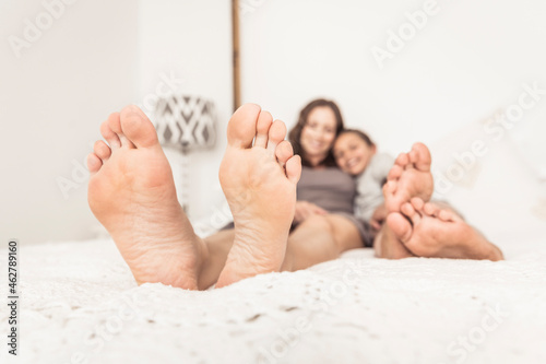 Crop view of mother and daughter lying barefoot on bed photo