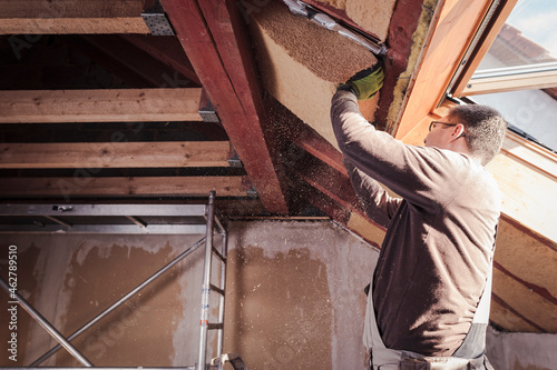 Roof insulation, worker filling pitched roof with wood fibre insulation
