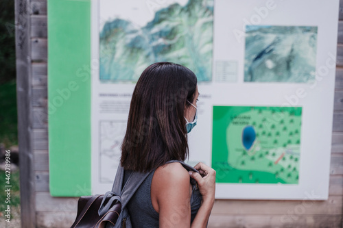 Female hiker wearing face mask looking at map photo