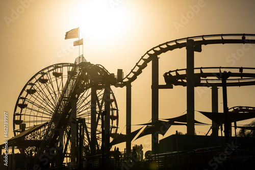 USA, California, Santa Monica, Silhouettes of Ferris wheel and rollercoaster of Santa Monica Pier at sunset photo