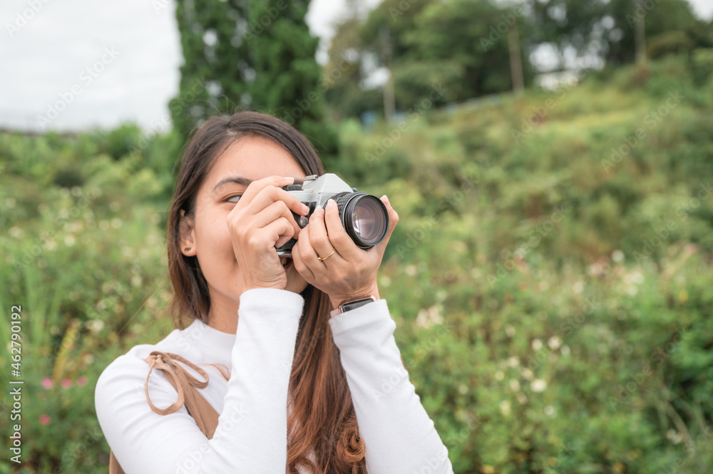 Young asian woman taking photo with retro film camera among the nature in the morning Young asian woman taking photo with retro film camera among the nature in the morning