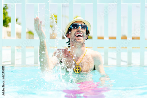 Happy man splashing water in swimming pool photo