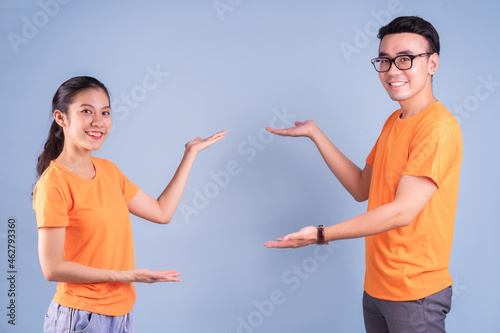 Young Asian couple wearing orange t-shirt on blue background