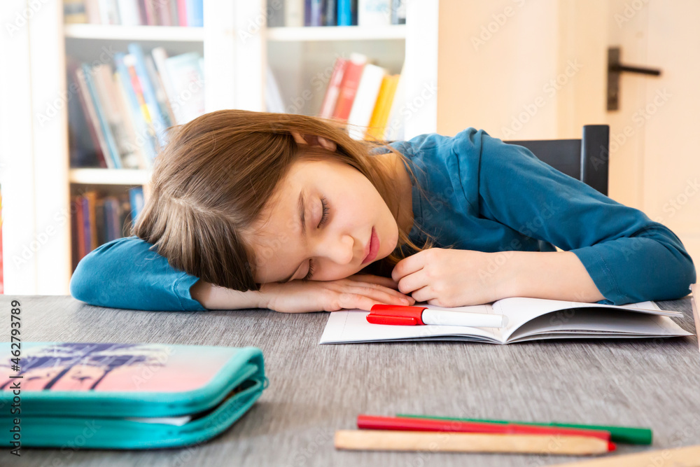 Schoolgirl napping at table with homework Schoolgirl napping at table with homework